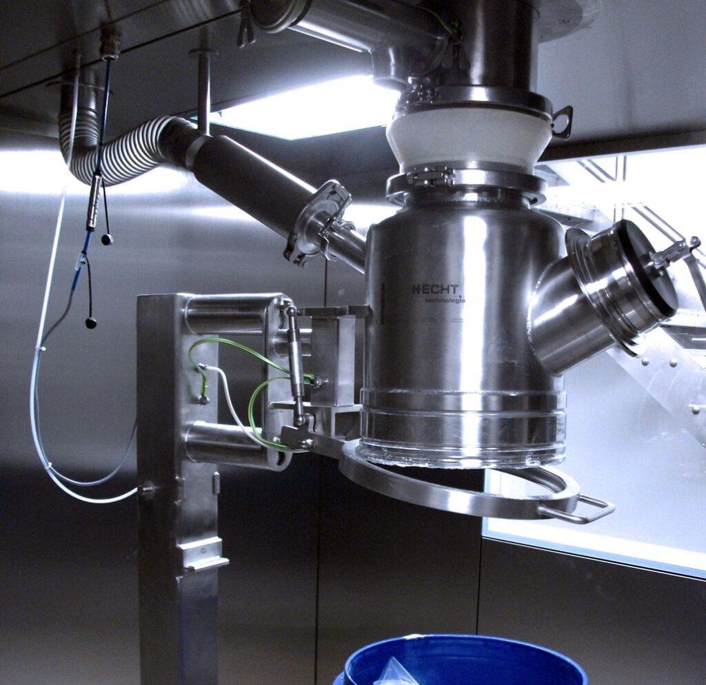 A HECHT LBK drum filling system featuring a stainless steel funnel connected to industrial piping, with an attached electronic monitoring device, poised over a blue collection bin for precision filling operations.