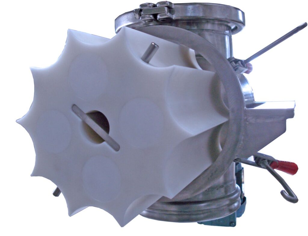 A HECHT dosing valve with a distinctive white star-shaped rotor housed within a metal frame. The apparatus includes manual levers and clamps for operation, typically used in the controlled release and dosing of powdered or granular materials in industrial settings.