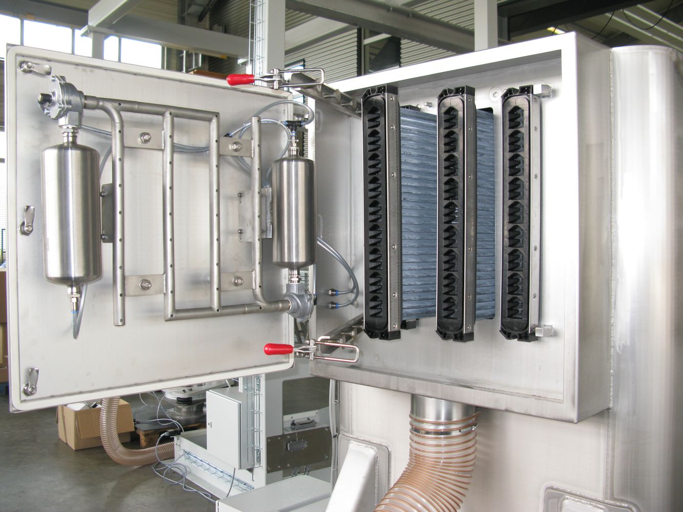 Stainless steel HECHT filtration system with multiple filter blocks in an open cabinet, featuring cylindrical filters and accordion-like flexible tubes. The system is designed for high-efficiency filtration with easy access for maintenance and cleaning in an industrial setting.