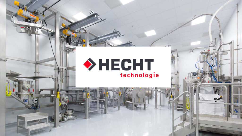 Spacious and clean industrial environment with HECHT technology equipment for material handling and processing. Overhead hoist systems and stainless steel machinery are arranged methodically on a glossy floor, with the HECHT logo prominently superimposed in the center.